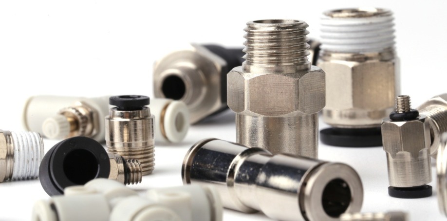 An extreme close up of metal pneumatic fittings accessories scattered across the blank white background.