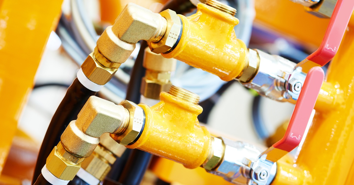 An extreme close-up of a yellow hydraulic pressure pipe and connection fittings of industrial equipment.