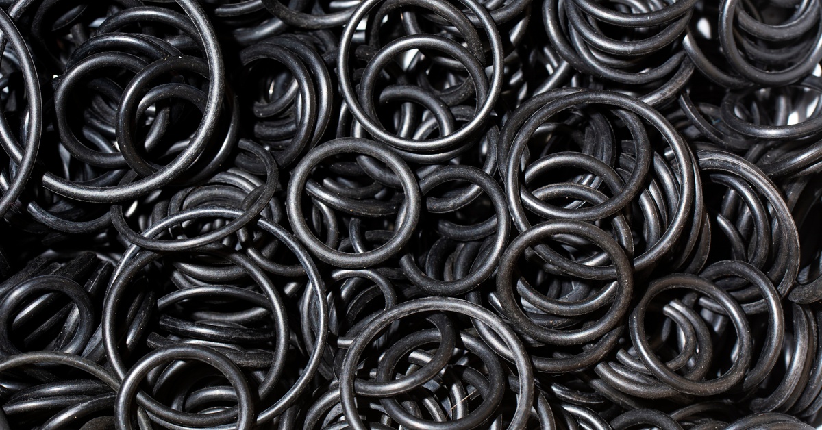 A multitude of black o-ring seals comprised of rubber, used in hydraulic systems, grouped together in a pile.