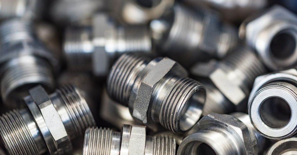A close-up and semi-focus of a large, disorganized pile of new male pipe industrial adapters in a container.