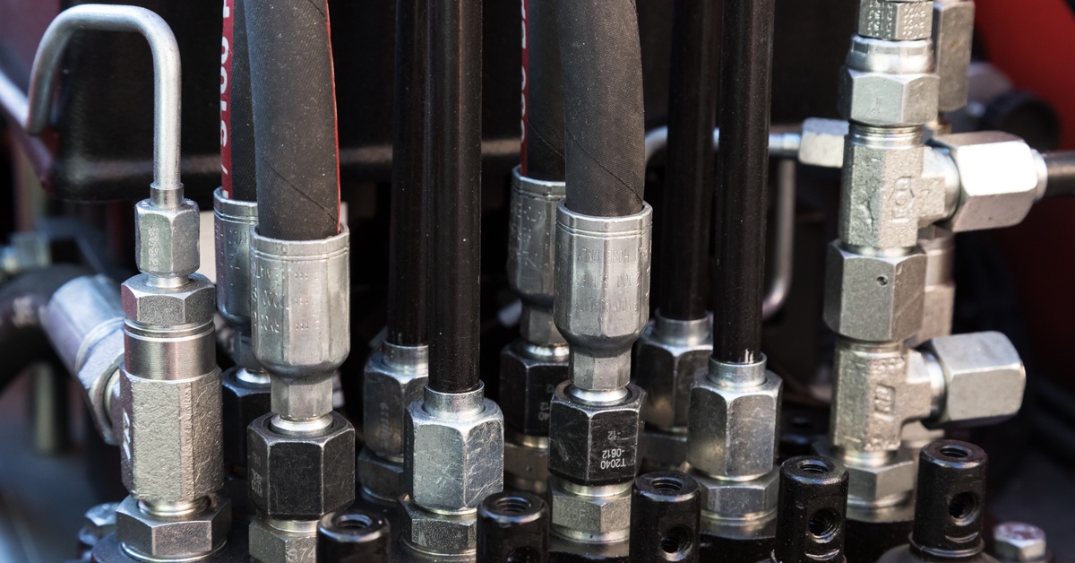 Hydraulic adapters, fittings, connectors, and couplings that attach to hoses are part of an industrial machine.