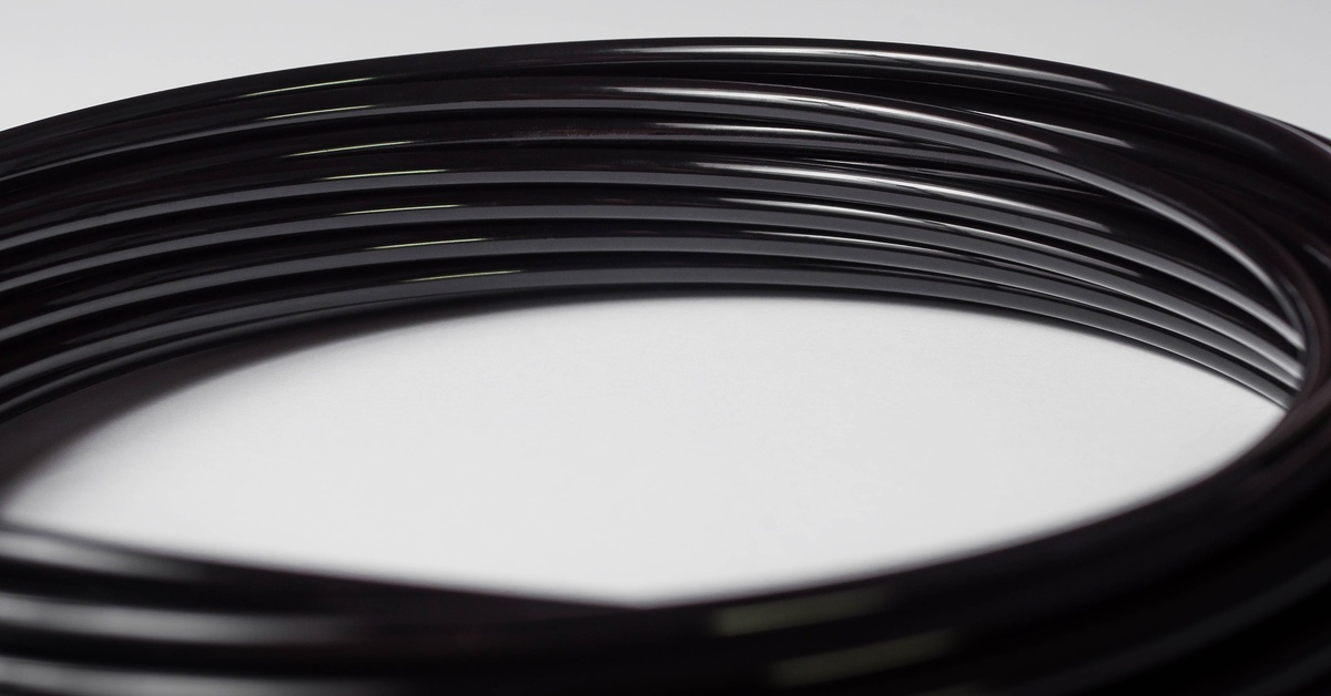 Black tubing for a pneumatic system wrapped in a circle. The black tubing sits against a plain white background.