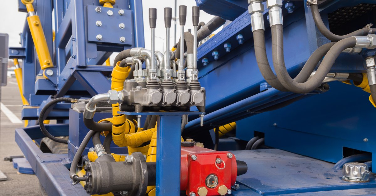 A hydraulic system with a blue exterior. There are hoses coming from various components and four levers.