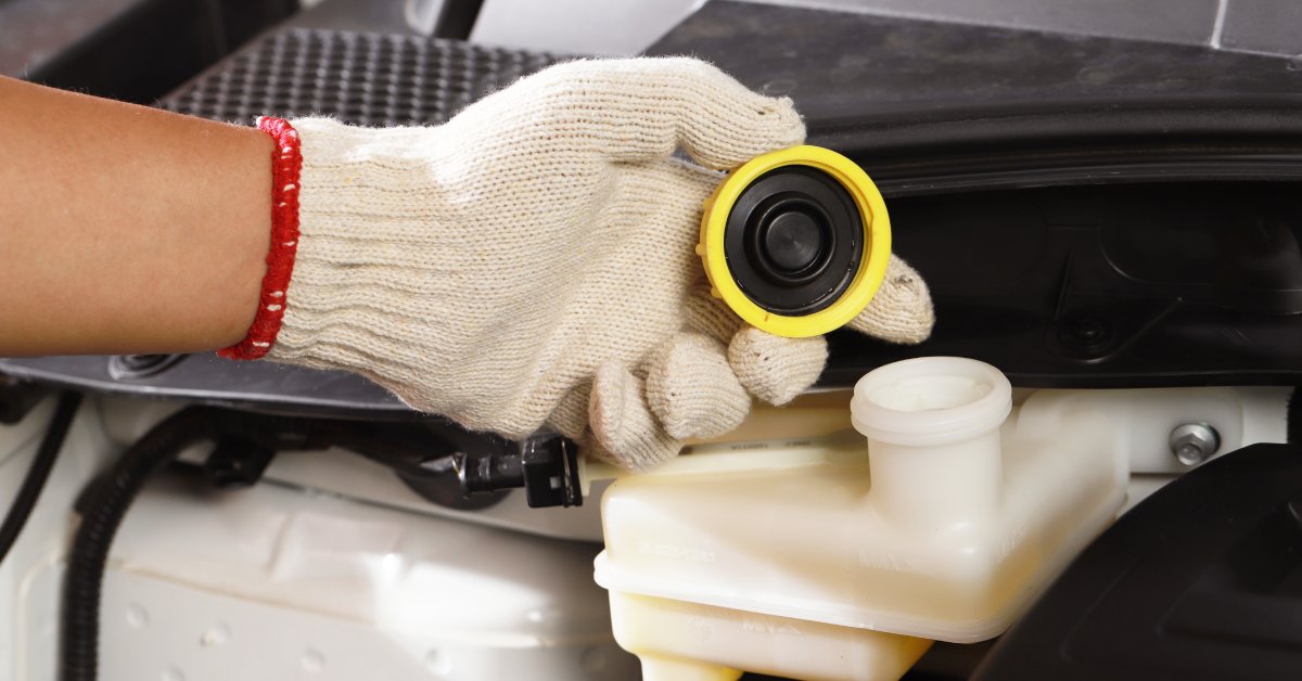 Someone wearing a white glove holds the cap to a fluid container inside a hydraulic system. The cap is very clean.