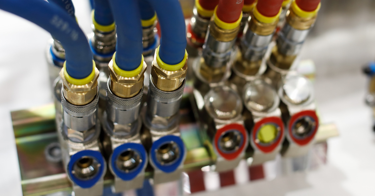 Several blue rubber air hoses and several red rubber air hoses, up close. Both hose types have pneumatic fittings.