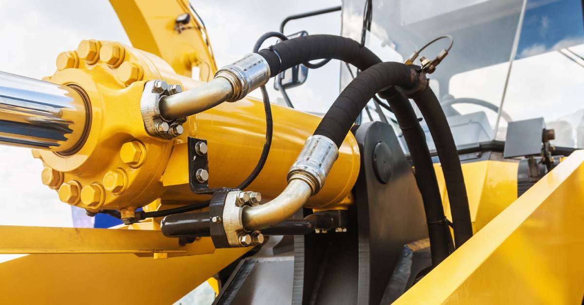 The image of a large, yellow hydraulics tractor and hydraulic pipes and nozzles used for industrial work.
