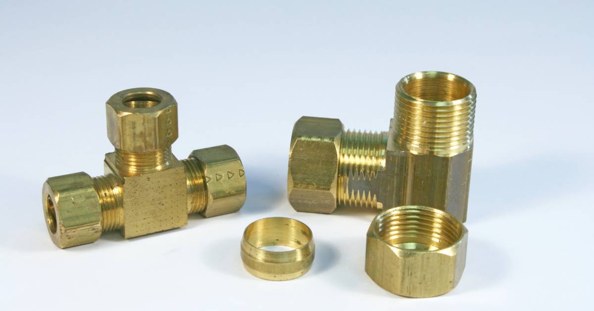 Industrial brass air compression fittings of different shapes and sizes grouped together on a plain surface.