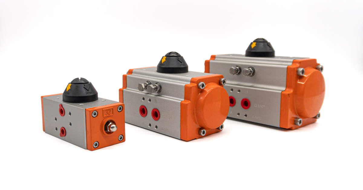 Three differently sized orange and gray pneumatic valves sitting together against a plain white surface.