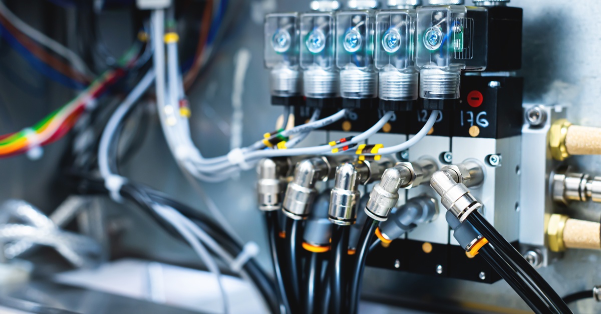 A pneumatic valve is attached to a wall and a pneumatic control board with hoses and connectors.