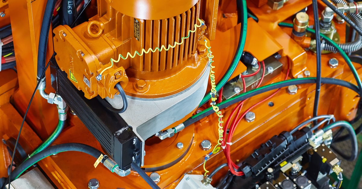 An orange hydraulic pump connected to hydraulic hoses and other components of an industrial oil drive system.