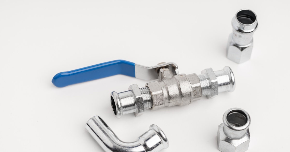 Several hydraulic fittings and a water control valve are grouped together and lying on a plain white surface.