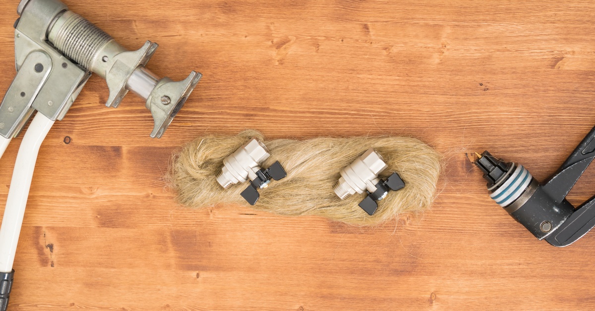 A pair of ball valves and a set of hydraulic tools for their installation lying on a wooden surface.