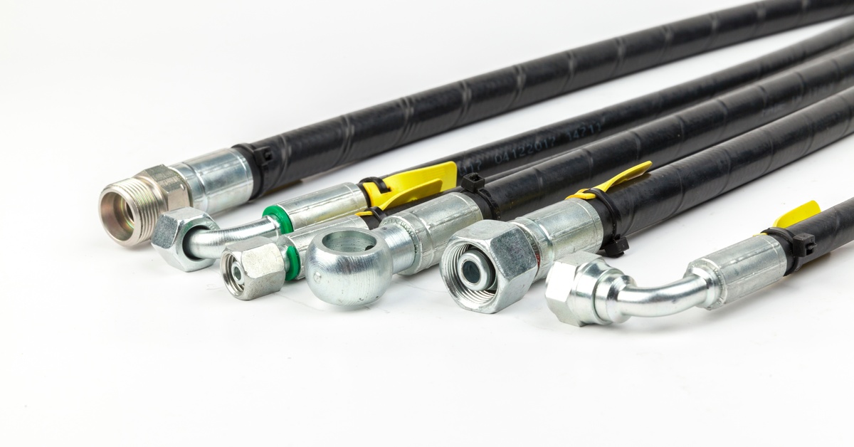 Several hydraulic hoses with connections attached to them spread out against a plain white background.