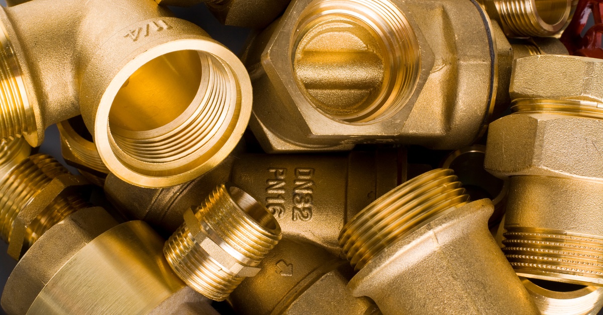 Several brass fittings assorted in a pile together against a plain background. The fittings have numbers on them.