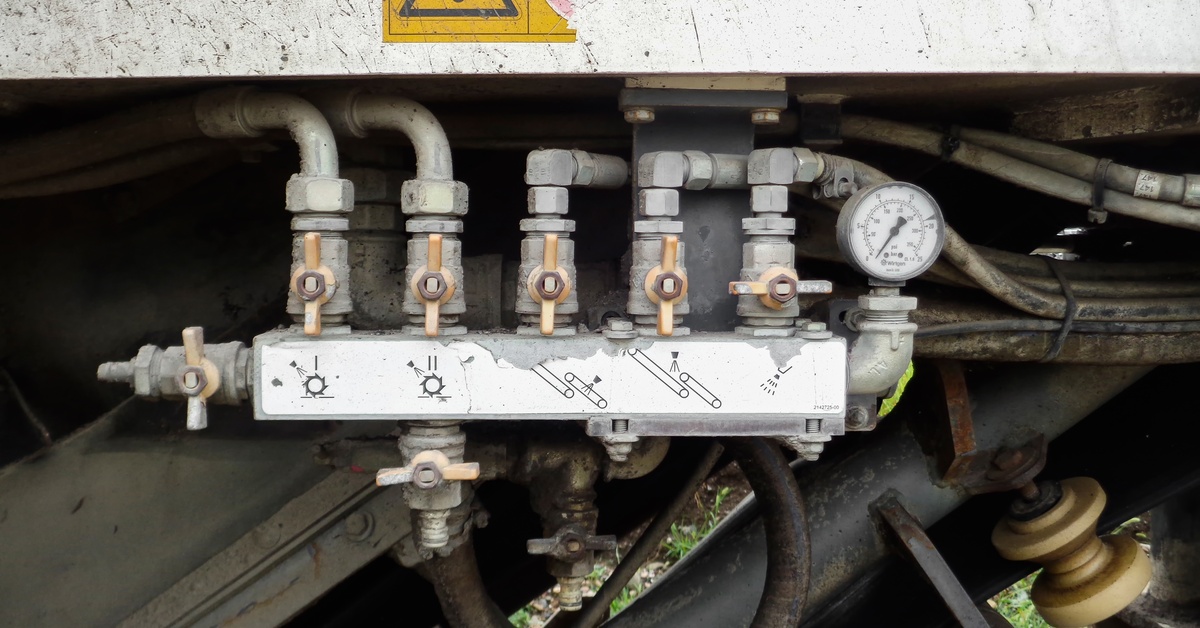 The valves, hoses, and fittings of a machinery control system that has spots of discoloration and corrosion.