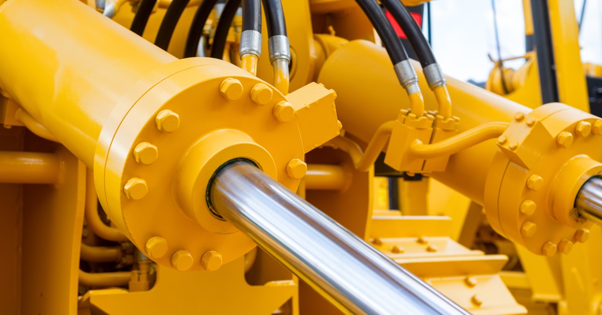 A close-up of large yellow hydraulic cylinders working as the main power and driving element for equipment.